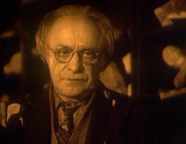 An old, white man wearing glasses. In sepia