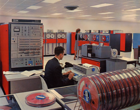 Photo of old computer room full of tape drives. The primary color is red.